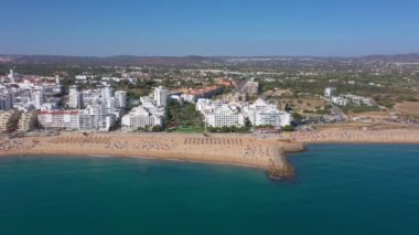 İnsansız hava aracı görüntüleri, Atlantik Okyanusu kıyısında turist kasabası Quareira 'yı çekiyor, turistlerle dolu plajlar. Portekiz, Algarve.
