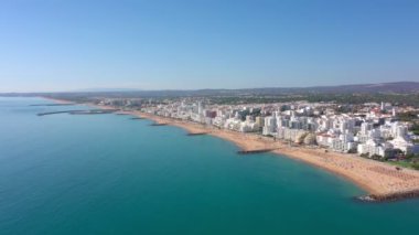 İnsansız hava aracı görüntüleri, Atlantik Okyanusu kıyısında turist kasabası Quareira 'yı çekiyor, turistlerle dolu plajlar. Portekiz, Algarve.