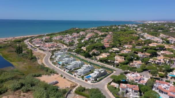 Luftaufnahme der Gebäude des Quinta do Lago Resorts in Vale de Lobo, Algarve, Portugal, Europa. Aufnahme von Dächern von Luxus-Ferienhäusern in grüner Landschaft mit Bergen im Hintergrund. Golfplätze. — Stockvideo