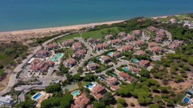 Vale de Lobo, Algarve, Portekiz, Avrupa 'daki Quinta do Lago tatil köylerinin hava manzarası. Yeşil manzaralı, arka planda dağlar olan lüks kulübelerin çatıları. Golf alanları.