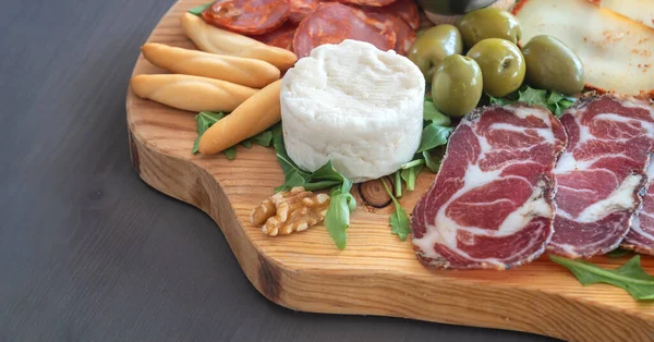 Very colorful tapas board of charcuterie with cheese and smoked meats. Decorated with arugula and walnuts. Wine snacks. Close up — Stock Photo, Image