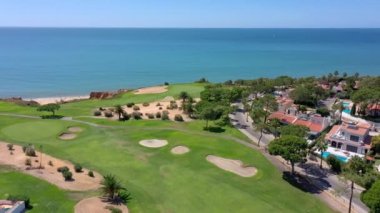 Vale de Lobo, Algarve, Portekiz, Avrupa 'daki Quinta do Lago tatil köylerinin hava manzarası. Yeşil manzaralı, arka planda dağlar olan lüks kulübelerin çatıları. Golf alanları.
