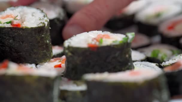 Der Koch legt sich hin, liefert Sushi und Semmeln aus Meeresfrüchten mit asiatischen Zutaten. Nahaufnahme, Makro. Der Hintergrund ist verschwommen. Zeitlupe — Stockvideo