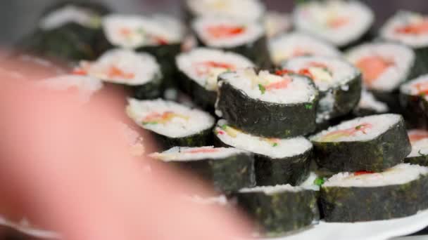 Kocken lägger ner, sätter för leverans bitar av sushi och rulle gjord av skaldjur med asiatiska ingredienser. Närbild, makro. Bakgrunden är suddig. — Stockvideo