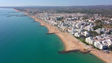 İnsansız hava aracı görüntüleri, Atlantik Okyanusu kıyısında turist kasabası Quareira 'yı çekiyor, turistlerle dolu plajlar. Portekiz, Algarve.