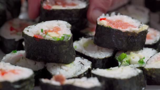 El chef se acuesta, establece para la entrega piezas de sushi y rollo de mariscos con ingredientes asiáticos. Primer plano, macro. El fondo está borroso. Movimiento lento — Vídeo de stock