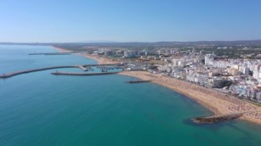 İnsansız hava aracı görüntüleri, Atlantik Okyanusu kıyısında turist kasabası Quareira 'yı çekiyor, turistlerle dolu plajlar. Portekiz, Algarve.