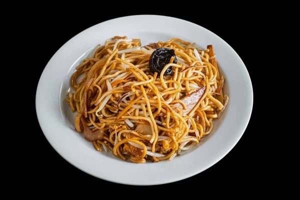 Nouilles asiatiques à la charrue avec poulet et légumes et champignons, dans une assiette blanche. Un plat oriental populaire. Sur fond noir. — Photo
