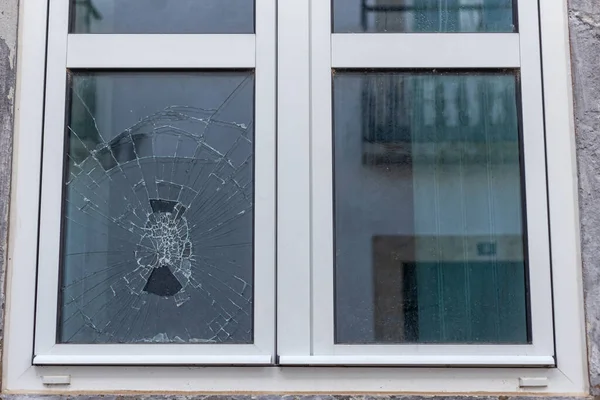 Vidrio agrietado en un marco de ventana de vacío de plástico. Una ventana dañada debido a vandalismo, desastre natural o accidente. — Foto de Stock