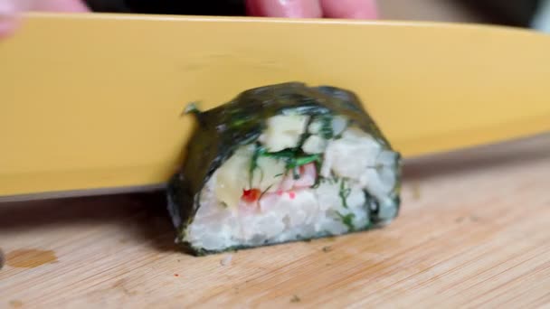 El chef corta sushi y rollos hechos de mariscos con ingredientes asiáticos con un cuchillo. Primer plano, macro. El fondo está borroso. — Vídeo de stock