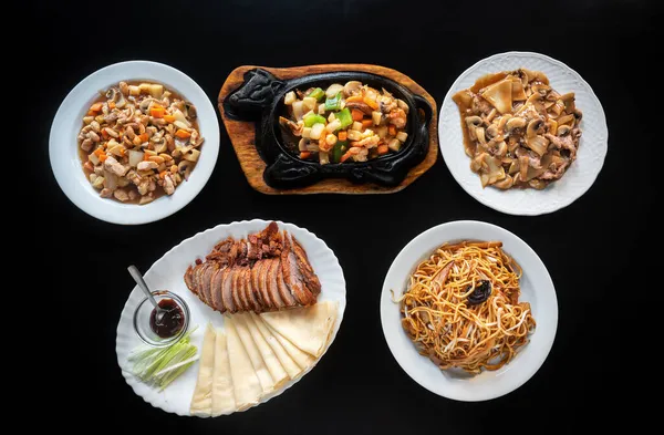 여러 종류의 아시아 요리들이 모여 있는 북경 오리 요리, 철로 만든 남비에 면 요리, 야채를 곁들인 새우 요리. 닭고기 스튜 아몬드, 당근, 파스타. 나막신 . — 스톡 사진