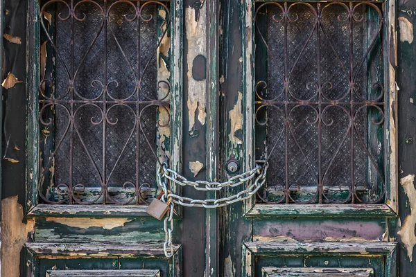 Dřevěné, starožitné dveře, zavřené železným řetězem a visacím zámkem. Detailní záběr. — Stock fotografie
