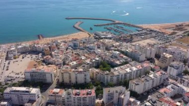 İnsansız hava aracı görüntüleri, Atlantik Okyanusu kıyısında turist kasabası Quareira 'yı çekiyor, turistlerle dolu plajlar. Portekiz, Algarve.