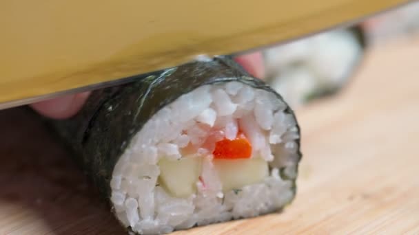 Kocken skär sushi och rullar av fisk och skaldjur med asiatiska ingredienser med kniv. Närbild, makro. Bakgrunden är suddig. — Stockvideo