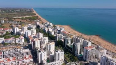 İnsansız hava aracı görüntüleri, Atlantik Okyanusu kıyısında turist kasabası Quareira 'yı çekiyor, turistlerle dolu plajlar. Portekiz, Algarve.