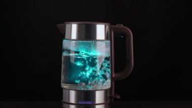 El, kaynar su, içecek, çay ya da kahve için bir bardak elektrikli su ısıtıcısı alır. Siyah bir arkaplanda.