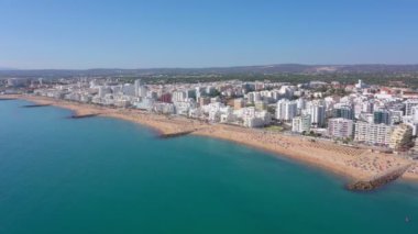 İnsansız hava aracı görüntüleri, Atlantik Okyanusu kıyısında turist kasabası Quareira 'yı çekiyor, turistlerle dolu plajlar. Portekiz, Algarve.