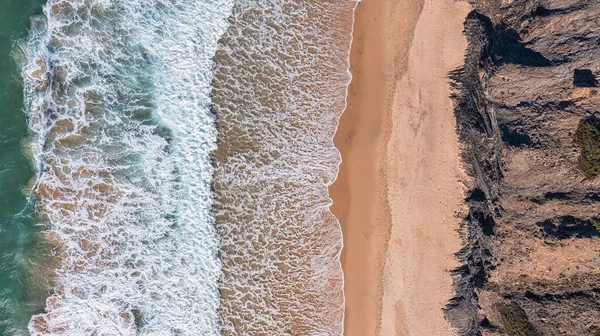 Widok z lotu ptaka na plażę i skały. Widok z lotu ptaka na fale morskie oraz turkusową wodę i fale. — Zdjęcie stockowe