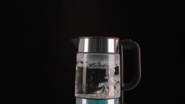 Une bouilloire électrique en verre moderne, fond noir, rempli d'eau à ébullition. Pour faire des boissons et de l'eau bouillante. bouillonnement en mouvement. — Video