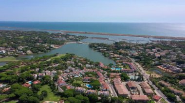 Vale de Lobo, Algarve, Portekiz, Avrupa 'daki Quinta do Lago tatil köylerinin hava manzarası. Yeşil manzaralı, arka planda dağlar olan lüks kulübelerin çatıları. Golf alanları.