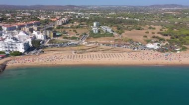 İnsansız hava aracı görüntüleri, Atlantik Okyanusu kıyısında turist kasabası Quareira 'yı çekiyor, turistlerle dolu plajlar. Portekiz, Algarve.