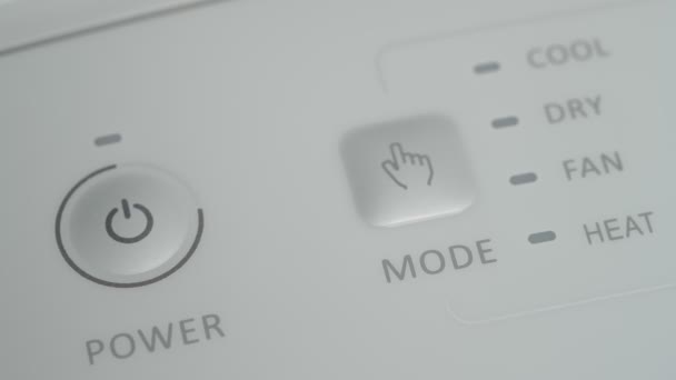 Человек нажимает кнопку "Пуск" на мобильном кондиционере, чтобы охладить комнату. Крупный план. — стоковое видео