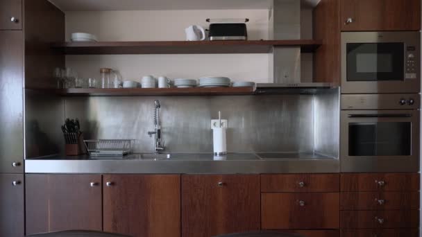Stojak z nowoczesnymi naczyniami kuchennymi w stylu inox metal. Schroniska kuchnia jest drewniane panele. — Wideo stockowe