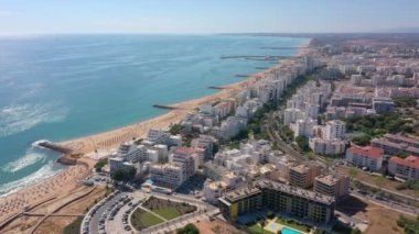 İnsansız hava aracı görüntüleri, Atlantik Okyanusu kıyısında turist kasabası Quareira 'yı çekiyor, turistlerle dolu plajlar. Portekiz, Algarve.