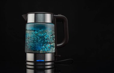 Kaynayan su için elektrikli cam çaydanlık. Sıcak içecekler için. Siyah arka planda köpüklü su..