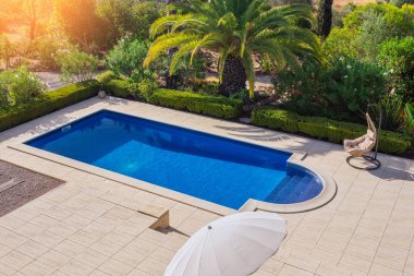 Bahçede modern bir havuz. Otelin yanında turistleri rahatlatmak için palmiye ağaçları var. Manzara, yaz, sallanan sandalye.