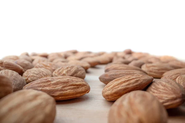 Group of almond nuts seeds in extreme close-up with short field of focus blurred in perspective. Nutrition, vitamins for vegetarians. Copy space — Stock Photo, Image