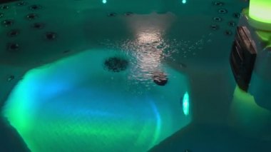 Terapi havuzu, kaplıca salonunda hidromasaj küveti, köpüklü ve temiz su, yakın çekim. Akşamları renkli romantik aydınlanma.