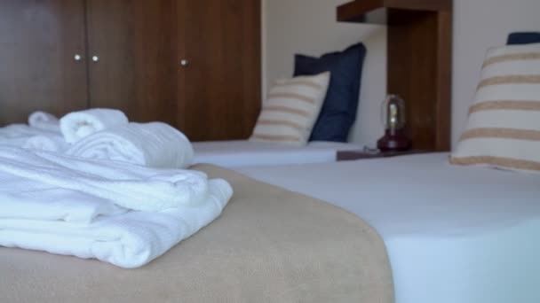 Video filmen van het hotel moderne slaapkamer kamer met bed en kussens. En witte handdoeken en een badjas voor hostel bezoekers. — Stockvideo