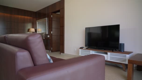 Moderne woonkamer in hout met een lederen sofa tafel en grote led, TV. — Stockvideo