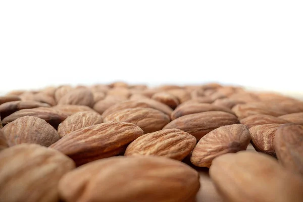 Group of almond nuts seeds in extreme close-up with short field of focus blurred in perspective. Nutrition, vitamins for vegetarians. Copy space — Stock Photo, Image