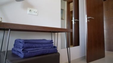 Masasında müşteriler için temiz mavi havlular ve lamba olan bir otel odası. Kaydırıcı atışı.