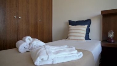 Yatak ve yastıklı modern otel odası videosu. Ve pansiyon ziyaretçileri için beyaz havlular ve bornoz..