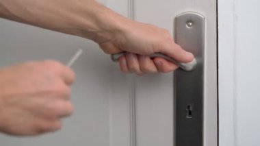 Adam bir anahtarla kapıyı açar ve giriş çıkış için kapıyı açar. Yakın plan. Konforlu mahremiyet ve güvenlik kavramı.