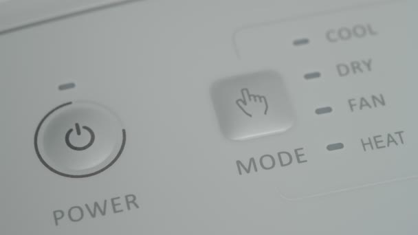 La personne appuie sur le bouton de démarrage avec son doigt sur un climatiseur mobile pour réchauffer la pièce en hiver. Gros plan. — Video