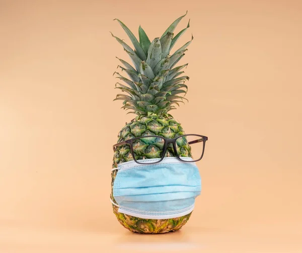 Interpretation of pineapple fruit in human form during a pandemic with glasses and a protective doctors mask. Copy space — Zdjęcie stockowe