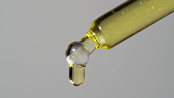 Drops of oil extract dripped from a glass pipette for chemical reactions and aromatherapy. Close up macro. — Stock Video