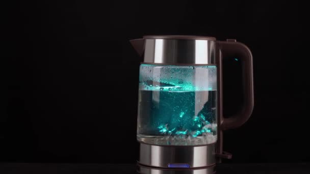 A modern glass electric kettle, on a black background, filled with water to boil. For making drinks and boiling water. seething in motion. — 비디오