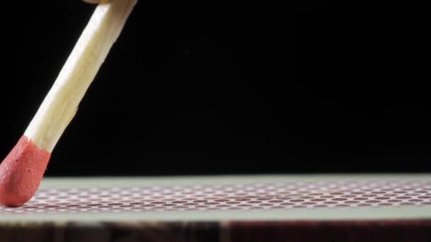 Zünden Sie einen Funken von einem Streichholz, indem Sie es gegen einen mit Schwefel beschichteten Kasten reiben. Auf schwarzem Hintergrund Nahaufnahme in einem Makro. — Stockvideo