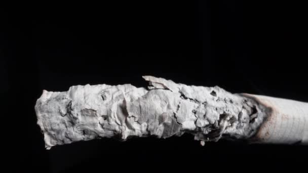 Smoke from a lit cigarette and ash Close-up on a black background. Smoking is hazardous to health — Vídeo de Stock