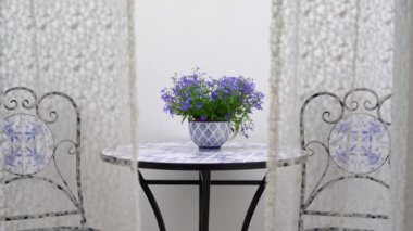 Romantik romantizm dekorasyonu ve balkon manzarası. Rüzgarın perdeleri arasından. Masada bir saksıyla..