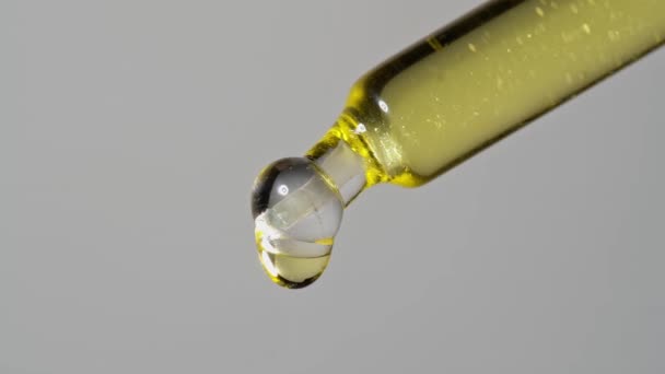 Drops of oil extract dripped from a glass pipette for chemical reactions and aromatherapy. Close up macro. — Stock video