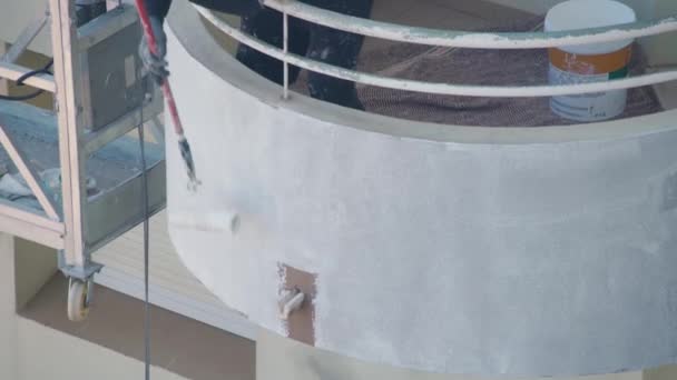 Profesjonalny malarz na windzie maluje ściany wielopiętrowego budynku na biało. — Wideo stockowe