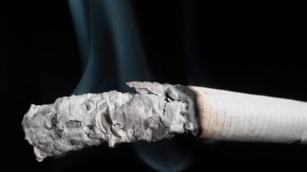 Humo de un cigarrillo encendido y ceniza Primer plano sobre un fondo negro. Fumar es peligroso para la salud — Vídeos de Stock