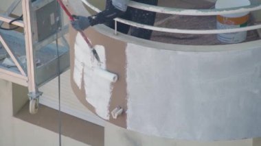 Asansördeki profesyonel bir ressam çok katlı bir binanın duvarlarını beyaza boyar..