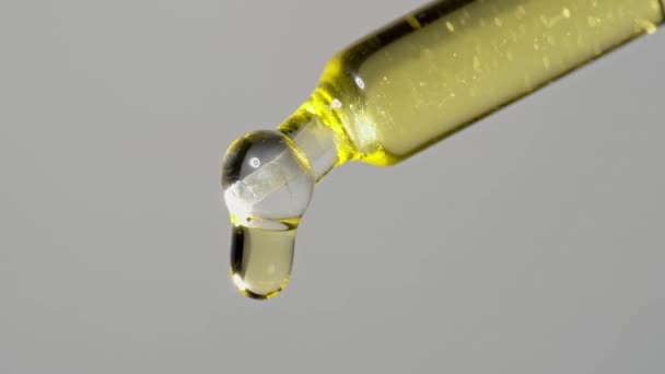 Druppels olie-extract druppelden uit een glazen pipet voor chemische reacties en aromatherapie. Sluiten macro. — Stockvideo